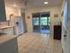 Bright kitchen with white appliances, sliding glass doors to a screened-in porch, and tiled floors at 11 Sandra Cir, New Smyrna Beach, FL 32168