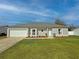 Charming single-story home featuring manicured lawn, flower beds, a gray roof, and a two-car garage at 3258 Cranston St, Deltona, FL 32738
