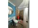 Bathroom featuring blue walls, tiled shower, and a large round mirror at 5165 Gwynne Ave, Orlando, FL 32810