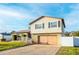 Two-story house with a large wooden garage door, landscaping, and a white picket fence at 610 Alton Rd, Winter Springs, FL 32708