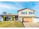 Tan two-story house with a large wooden garage door, landscaping, and a white picket fence at 610 Alton Rd, Winter Springs, FL 32708