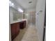Bathroom with a double sink vanity, granite counters, framed mirror, and a glass-enclosed walk-in shower at 8343 Bella Tierra Ct # 8343, Davenport, FL 33896