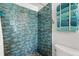 Tiled shower with blue accents, complemented by a stack of neatly folded towels at 1608 Bomi Cir, Winter Park, FL 32792