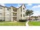 Multi-story condo building with balconies, red tile roof, green lawn, and a sidewalk leading to a community pool at 3032 Parkway Blvd # 302, Kissimmee, FL 34747