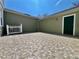 An exterior view of a paved patio with white picket fence and a green exterior wall under a blue sky at 7128 Five Oaks Dr, Harmony, FL 34773