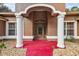 Inviting home exterior with a red walkway, arched entryway, and columns at 6900 Sw 137Th Court Rd, Ocala, FL 34481