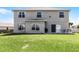 Spacious backyard view of the two-story home featuring a concrete patio, a grill, and a grassy lawn at 1907 Lakeview Way, Kissimmee, FL 34759