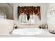 Bathroom featuring an inviting soaking tub under a window with decorative accents and towels at 1907 Lakeview Way, Kissimmee, FL 34759