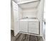 Convenient laundry area with side-by-side washer and dryer, complemented by overhead shelving and wood-look vinyl flooring at 1918 Conway Rd # 3, Orlando, FL 32812
