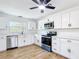 Modern kitchen featuring white cabinets, stainless steel appliances, quartz countertops, and wood-look flooring at 4317 Ne 12Th St, Ocala, FL 34470