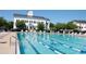 Full swimming pool with swimmers, deck chairs, and a view of an elegant building at 5342 Horton Ln, Orlando, FL 32814