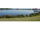A calm lake view with lush green grass in the foreground and a glimpse of a red-roofed gazebo at 5342 Horton Ln, Orlando, FL 32814