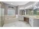 Bright bathroom featuring a soaking tub, glass block window, and a spacious vanity with dual sinks at 571 Masalo Pl, Lake Mary, FL 32746