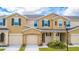 Tan two-story townhome with two-car garage and landscaping at 5149 Adelaide Dr, Kissimmee, FL 34746
