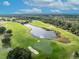 Scenic aerial view of a lush golf course with a tranquil pond and well-manicured greens at 7409 Wing Span Way, Harmony, FL 34773