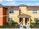 Inviting yellow townhouse featuring a well-kept lawn and a charming tile roof at 8939 Bismarck Palm Rd, Kissimmee, FL 34747