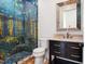 Charming bathroom featuring an artistic tiled shower, a vanity with marble countertop, and a well-lit mirror at 10214 Chiltern Garden Dr, Orlando, FL 32827