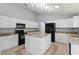 Bright kitchen featuring white cabinetry, a center island, and black appliances under a vaulted ceiling at 4731 Summerbridge Cir, Leesburg, FL 34748