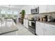Kitchen features a gray countertop, stainless steel appliances, white cabinetry, and natural light from the windows at 6115 Claystone Way, Mount Dora, FL 32757