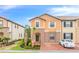 Two-story townhome with orange exterior, landscaping, and a driveway at 8851 Geneve Ct, Kissimmee, FL 34747