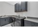 Functional laundry room with modern appliances, dark cabinets, ample counter space, and tile flooring at 15155 Mayberry Dr, Winter Garden, FL 34787