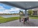 Covered patio with brick flooring features outdoor seating overlooking a serene lake and community landscape at 15155 Mayberry Dr, Winter Garden, FL 34787