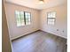 This bedroom features two large windows that bring in natural light and grey wood-style floors at 19942 Se 155Th Pl, Umatilla, FL 32784