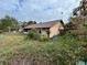Tan house exterior with brown roof and overgrown landscaping at 2708 Sedgefield Avenue, Deltona, FL 32725