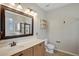 Bathroom with warm wood cabinets, white sink, mirror, and tiled shower at 2829 Shelburne Way, St Cloud, FL 34772