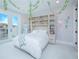 Charming bedroom with a built-in bookcase headboard, adorned with whimsical ivy and wall decorations at 13779 Abberwick Dr, Orlando, FL 32832