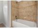 Bathroom showcasing a white tub with tiled walls, complemented by neutral-colored floor tiles at 2806 Balforn Tower Way, Winter Garden, FL 34787