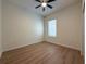 A well lit bedroom with a window, ceiling fan, hardwood flooring, and baseboards at 2806 Balforn Tower Way, Winter Garden, FL 34787