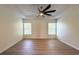 A bedroom features a tray ceiling with fan and light, hardwood floors, and two windows at 2806 Balforn Tower Way, Winter Garden, FL 34787