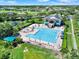 Aerial view of a sparkling community pool with sun loungers, umbrellas, and clubhouse at 2806 Balforn Tower Way, Winter Garden, FL 34787