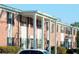 Red brick apartment building with white support beams, green landscaping, and a vehicle at 5317 Curry Ford Rd # J101, Orlando, FL 32812