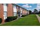 Red brick apartment building with black shutters, green lawn, and sidewalk under blue sky at 5317 Curry Ford Rd # J101, Orlando, FL 32812
