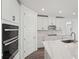 Modern kitchen showcasing quartz countertops, white cabinetry, stainless steel appliances, and sleek gray wood-look flooring at 2316 Citrus Bloom Dr, Bartow, FL 33830