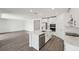 Well-lit kitchen showcasing white cabinets, stainless steel appliances, a center island, and sleek wood-look floors at 2316 Citrus Bloom Dr, Bartow, FL 33830