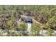 Aerial view of charming single-story home featuring a white exterior, dark garage door, and surrounded by dense forest at 406 Nw Narcissus Rd, Dunnellon, FL 34431