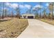 Charming single-story home featuring a white exterior, dark garage door, and a well-manicured lawn surrounded by tall trees at 406 Nw Narcissus Rd, Dunnellon, FL 34431