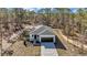 Aerial view of charming single-story home featuring a white exterior, dark garage door, and a well-manicured lawn surrounded by trees at 406 Nw Narcissus Rd, Dunnellon, FL 34431