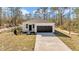 Charming single-story home featuring a white exterior, dark garage door, and a well-manicured lawn surrounded by tall trees at 406 Nw Narcissus Rd, Dunnellon, FL 34431