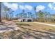 Charming single-story home featuring a white exterior, dark garage door, and a well-manicured lawn surrounded by tall trees at 406 Nw Narcissus Rd, Dunnellon, FL 34431