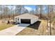 Charming single-story home featuring a white exterior, dark garage door, and a well-manicured lawn surrounded by tall trees at 406 Nw Narcissus Rd, Dunnellon, FL 34431