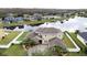 Aerial view of house with a large yard, brick driveway, lake view, and well-manicured landscaping at 3301 Buckingham Way, St Cloud, FL 34772