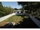 Spacious backyard featuring a well-maintained lawn, white fencing, brick patio, and a charming fire pit at 5255 Seminole Ave, Winter Park, FL 32792