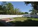 Secluded backyard featuring a well-maintained lawn, white fencing, brick patio, and a charming fire pit at 5255 Seminole Ave, Winter Park, FL 32792