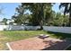 Secluded backyard featuring a well-maintained lawn, white fencing, brick patio, and a charming fire pit at 5255 Seminole Ave, Winter Park, FL 32792