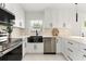 Modern kitchen featuring white cabinets, stainless steel appliances, a black farmhouse sink, and marble countertops at 5255 Seminole Ave, Winter Park, FL 32792