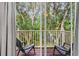 Screened balcony with patio chairs and a view of the lush greenery that the property backs up to at 8443 Crystal Cove Loop, Kissimmee, FL 34747